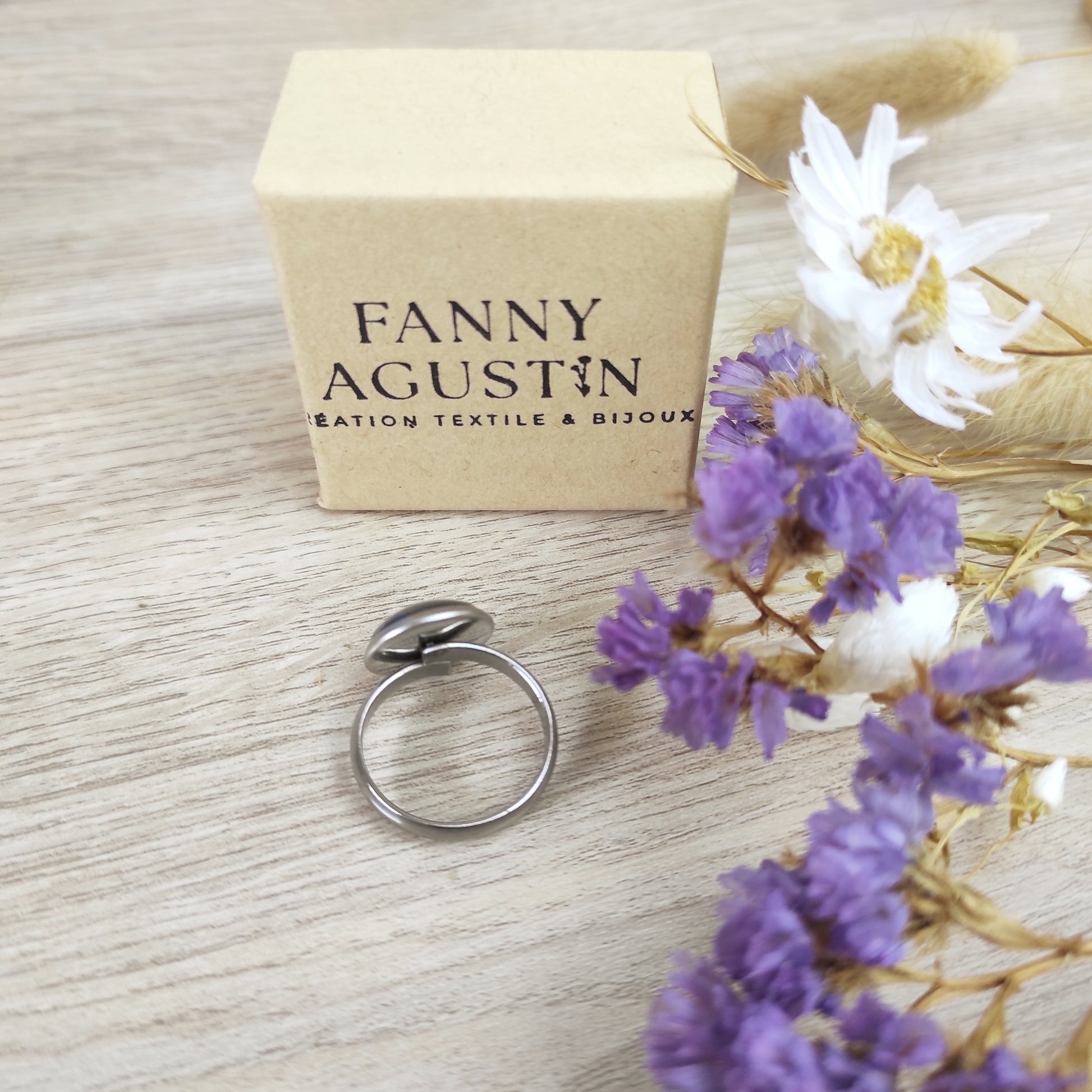 Bague réglable acier inoxydable couleur argentée vue de dos, placée à côté du coffret avec logo Fanny Agustin.