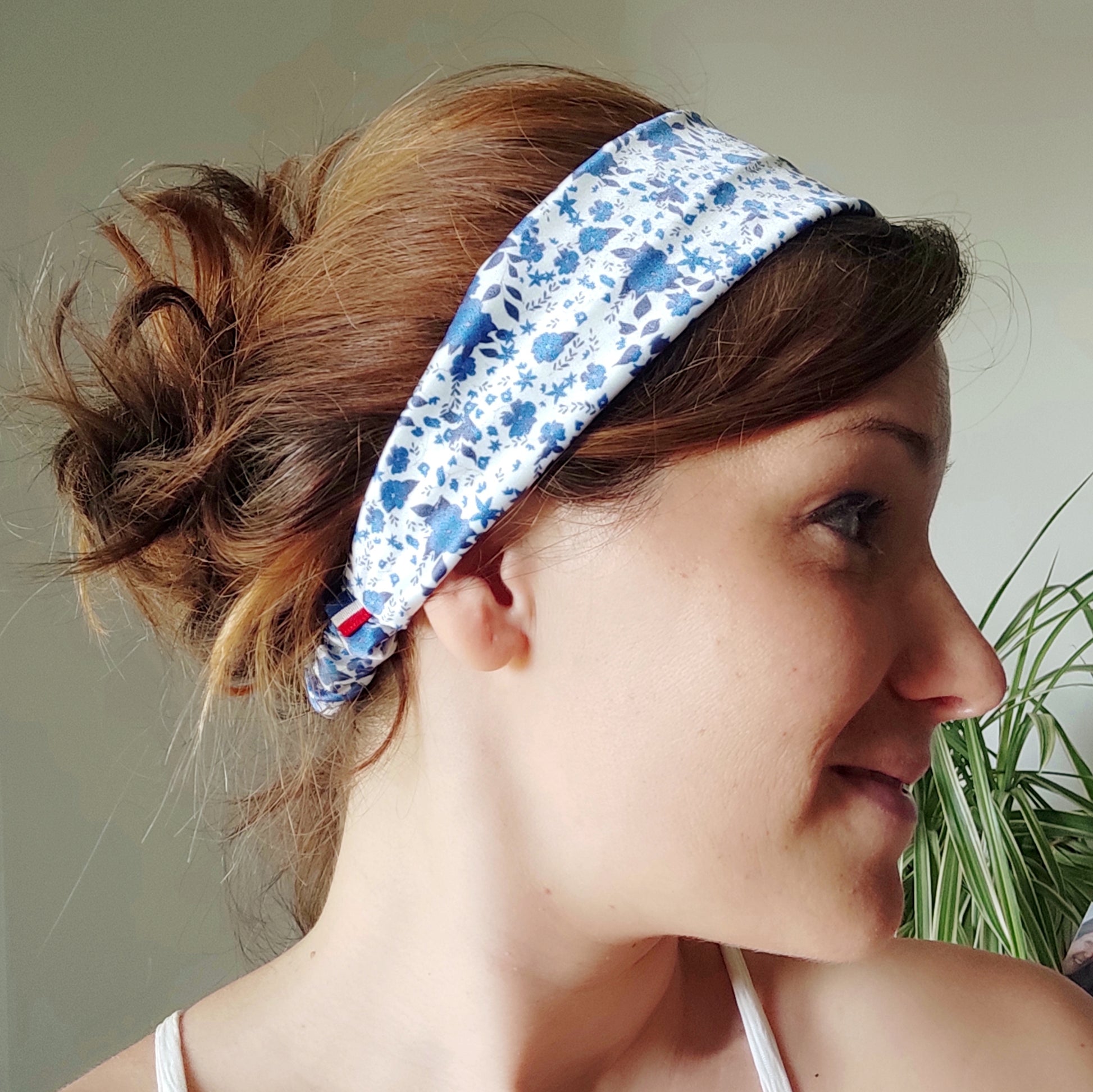 Accessoire pour cheveux, bandeau en satin avec motif fleuri dessiné par Fanny Agustin. Le bandeau est porté par une femme, le motif est bleu et blanc.