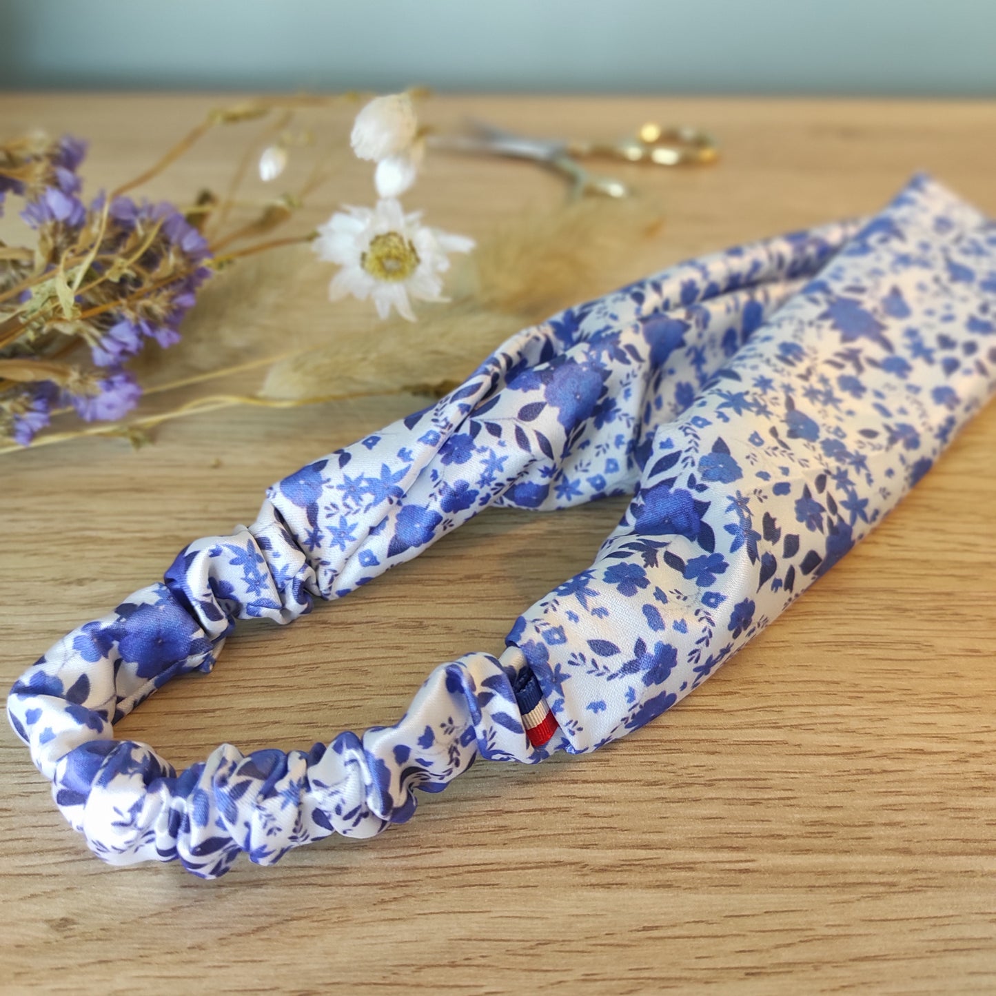 Accessoire pour cheveux, bandeau en satin avec motif fleuri dessiné par Fanny Agustin, couleur bleu et blanc.