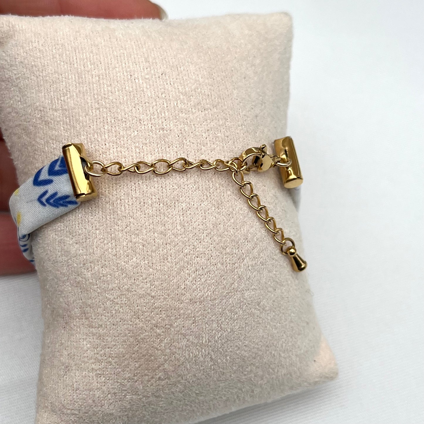 Bracelet en tissu signé Fanny Agustin, le motif est bleu jaune et blanc, il représente du mimosa. Le fermoir est doré et réglable.