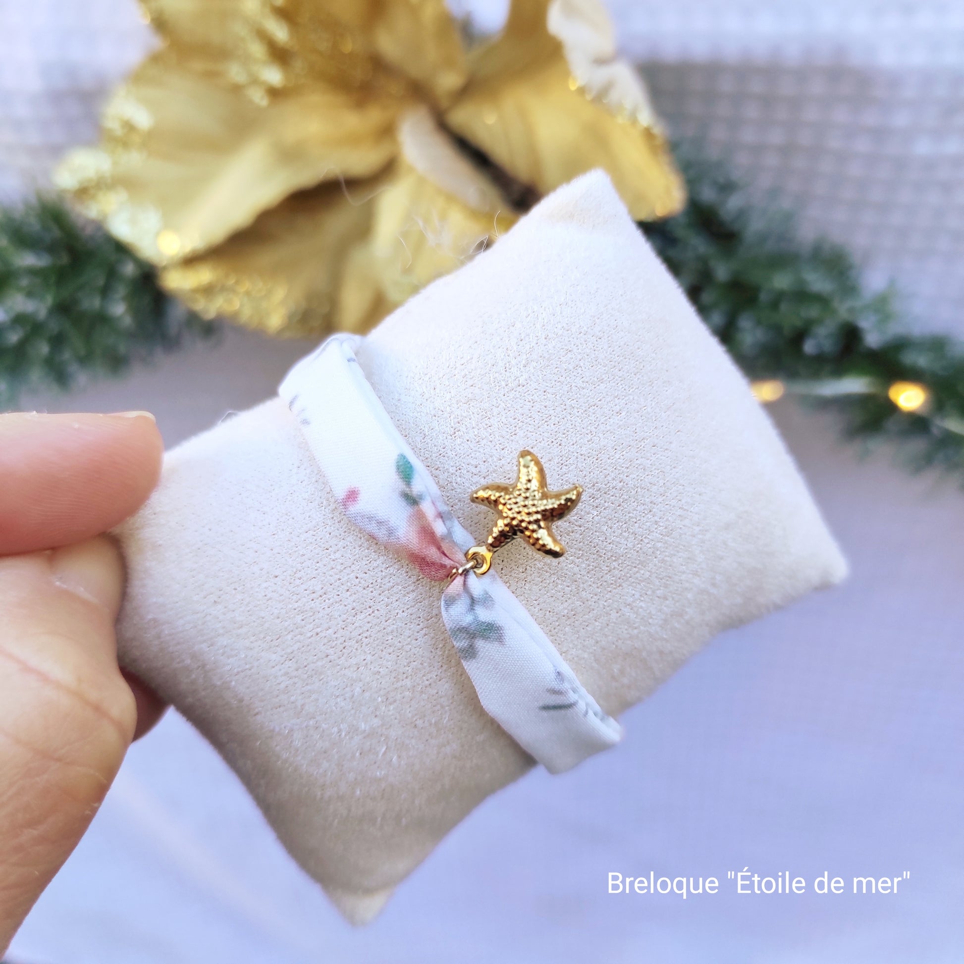 Bracelet en tissu création Fanny Agustin, motif fleurs saumonées et blanc avec quelques touches de vert. La breloque étoile de mer est dorée.