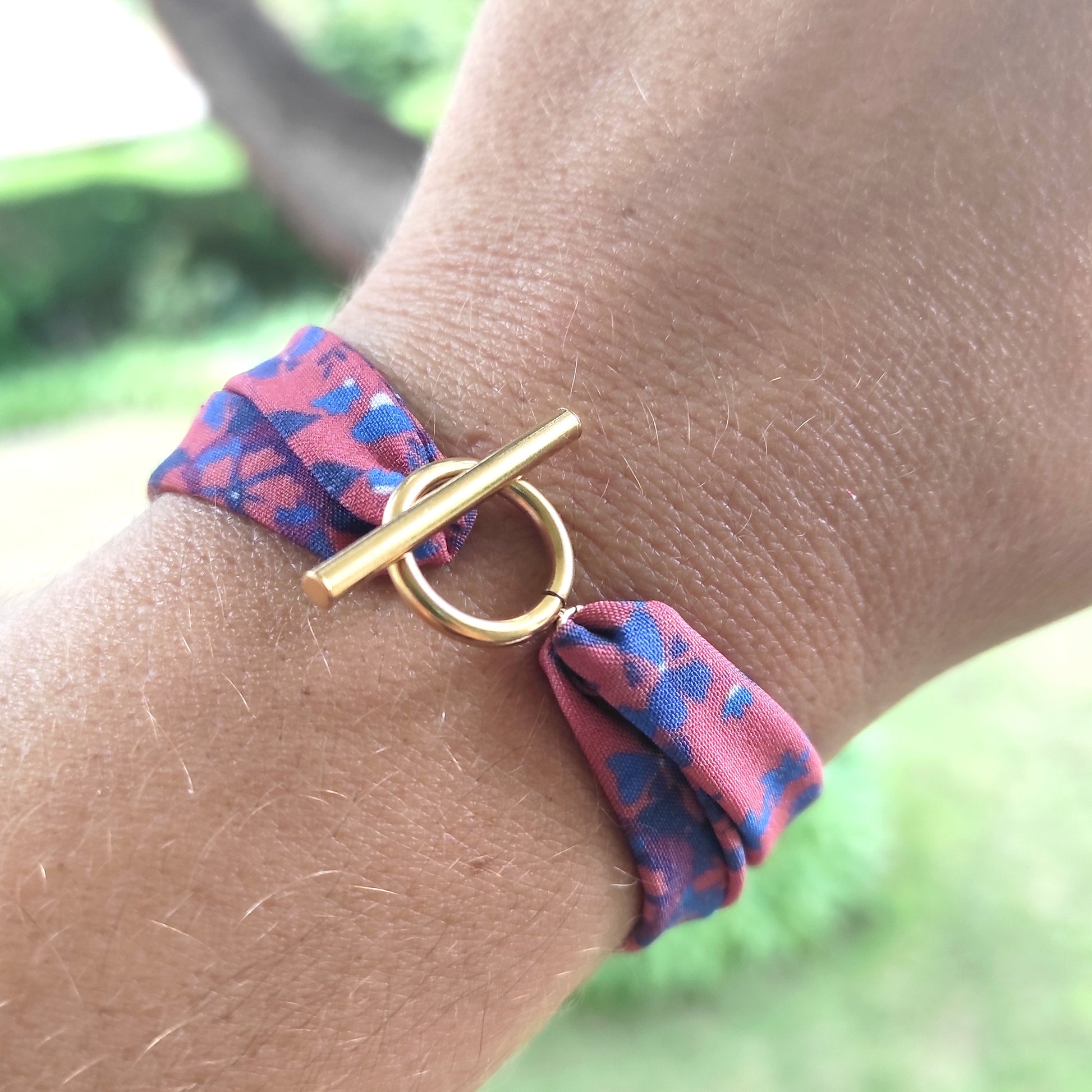 Bracelet tissu motif fleurs bleues fond paprika et fermoir doré.