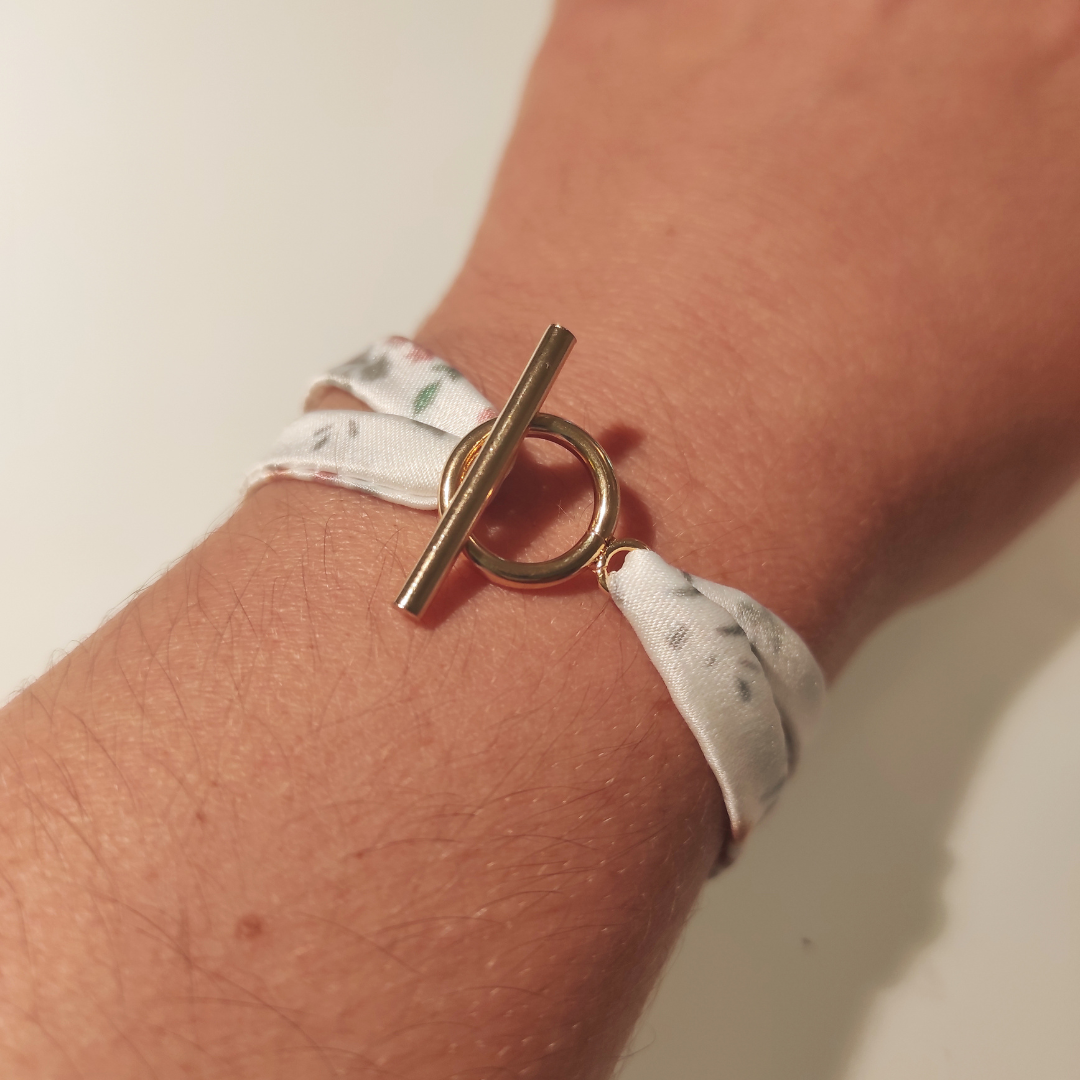 Bracelet en tissu satin motif fleurs aquarelle , fond blanc avec quelques touches végétation et fleurs saumonées , jaunes. Avec fermoir anneau en acier inoxydable.