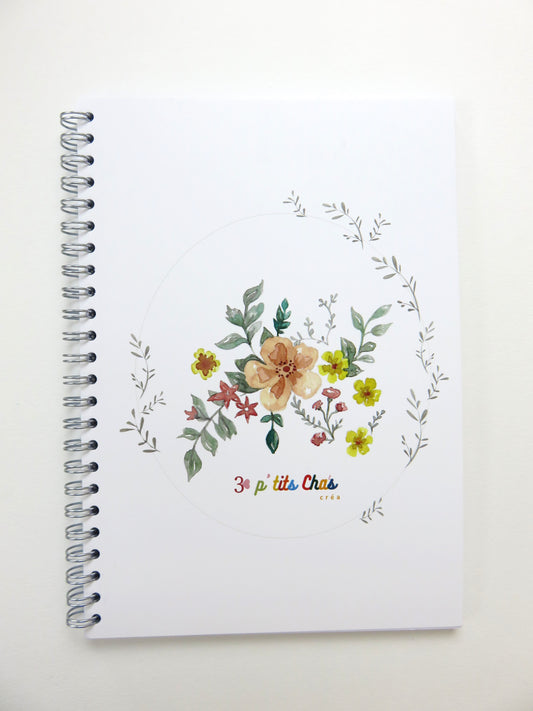 Cahier à spirales avec fond blanc et dessin de fleurs.