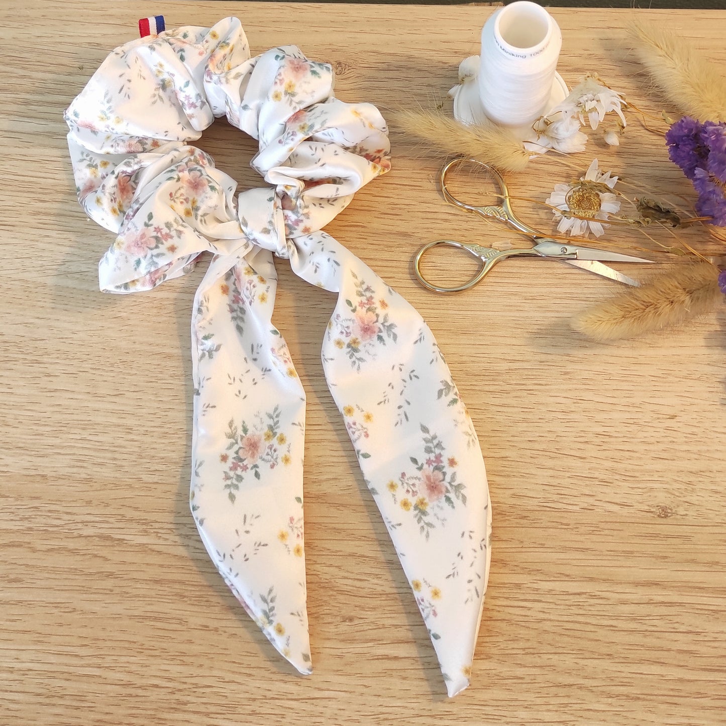 Chouchou foulchie motif en satin avec ruban détachable, motif fleurs aquarelle. Le ruban est blanc et comporte quelques fleurs avec du jaune, rose, feuilles vertes.