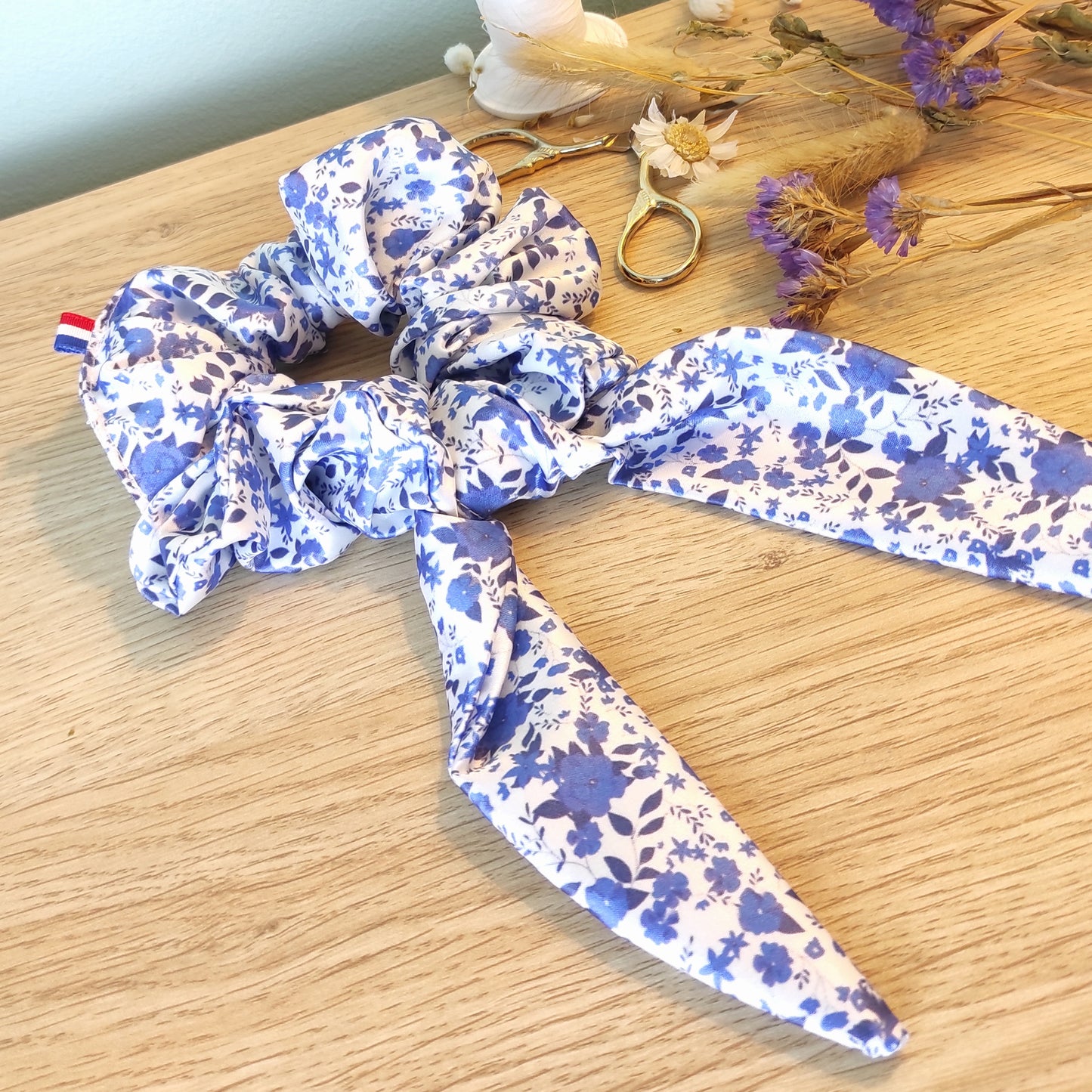Chouchou foulchie motif fleuri avec fleurs bleues et fond blanc.