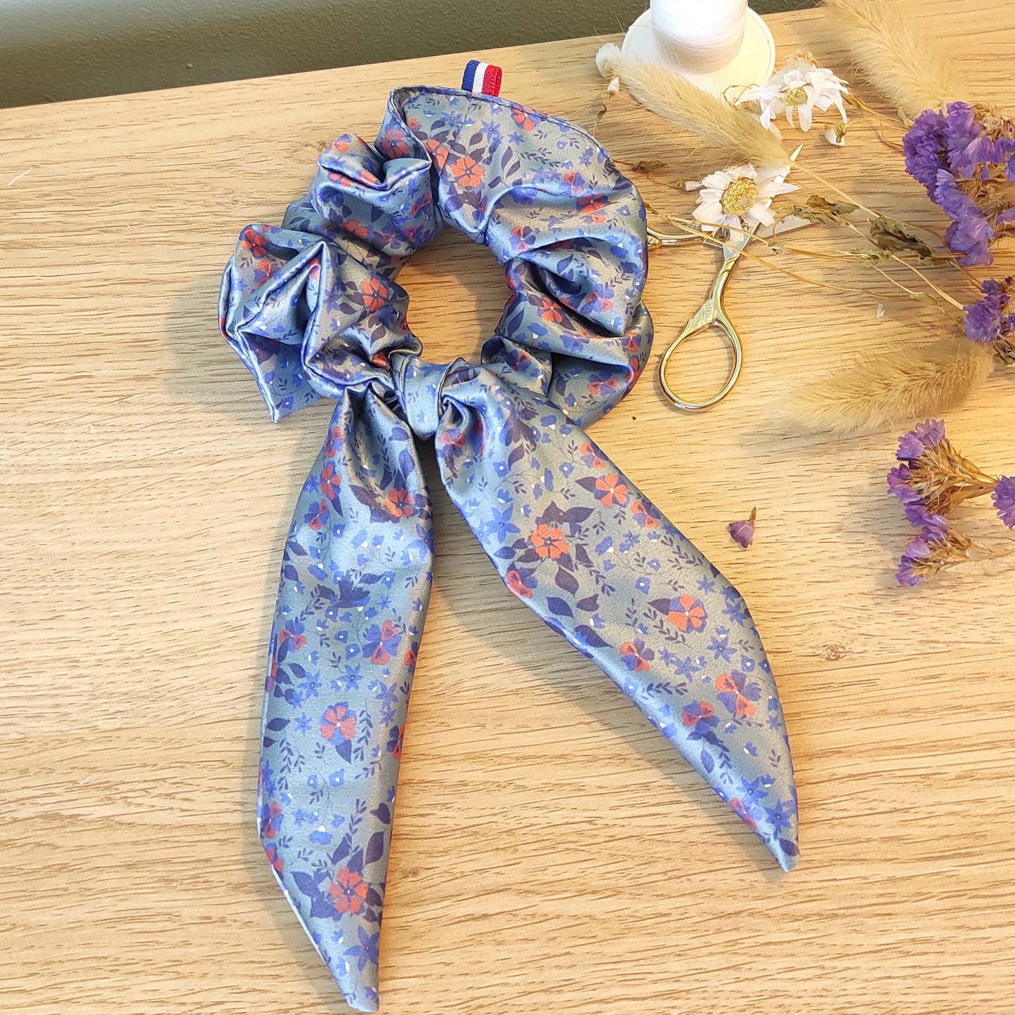Chouchou foulchie motif fleuri, fleurs bleues et papika, sur fond bleu.