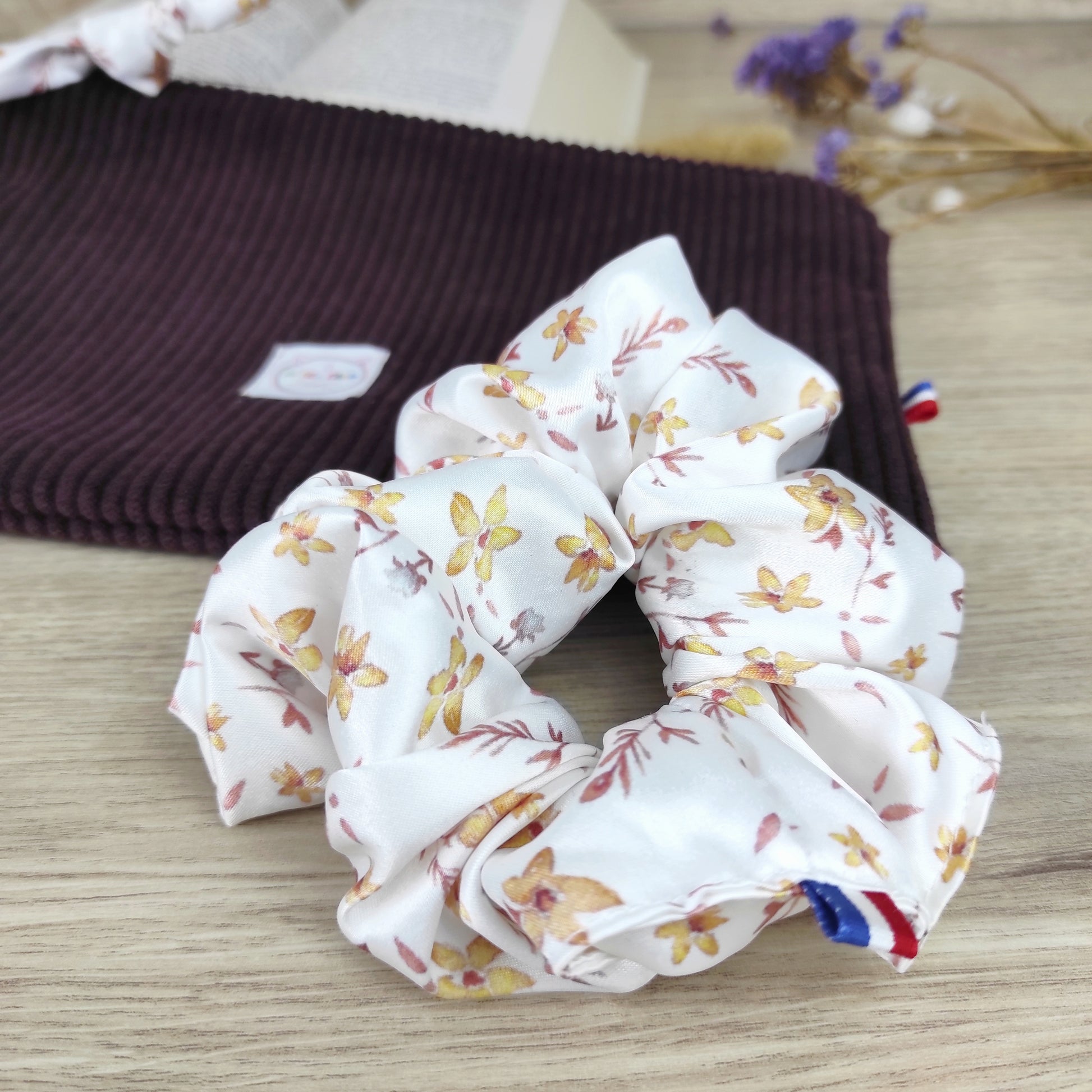 Chouchou blanc avec fleurs jaunes dorées et blanches, feuillage marron. Motif dessiné par Fanny Agustin.