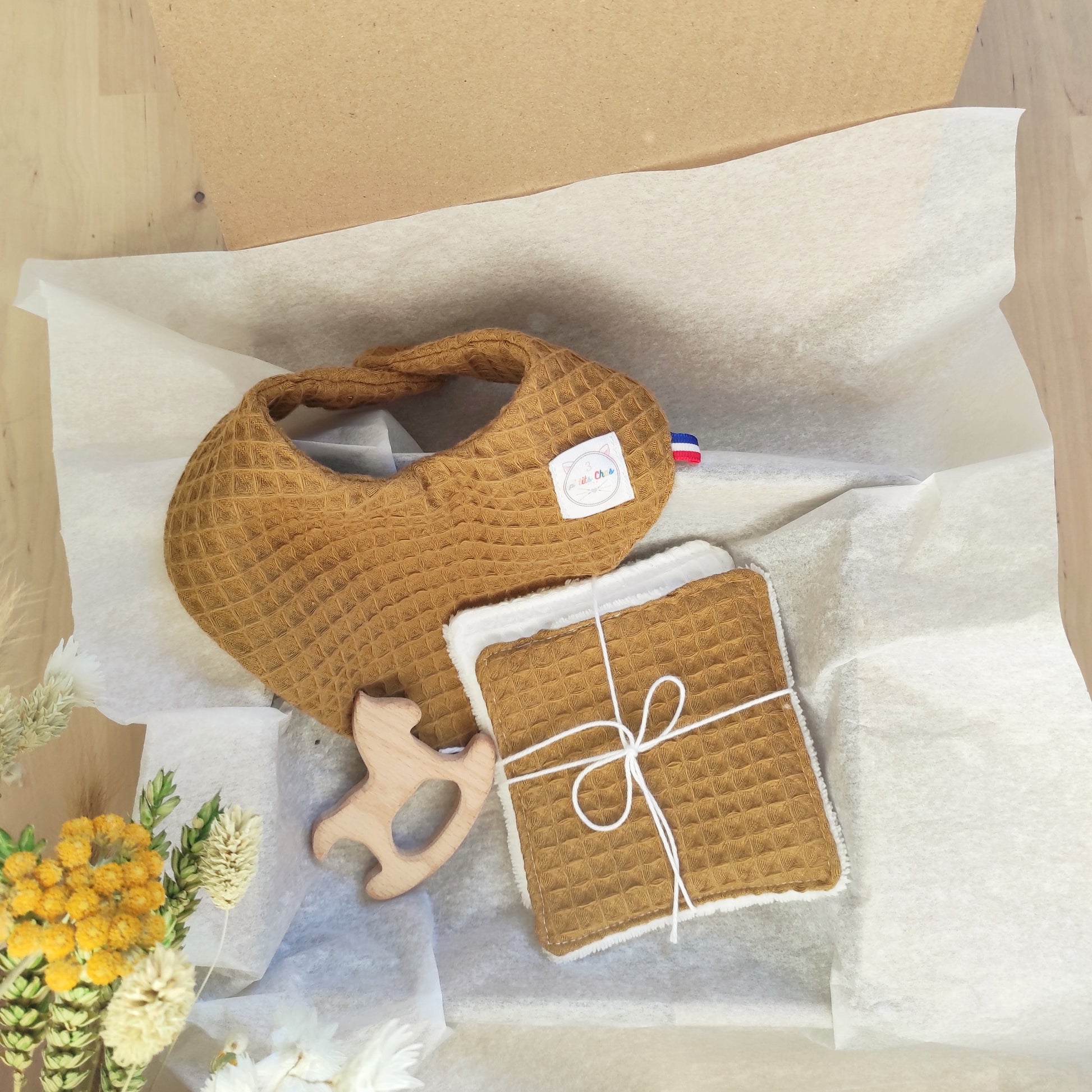 Kit naissance dans le coffret avec bavoir bandana, lingettes en nid d'abeille et hochet en bois.