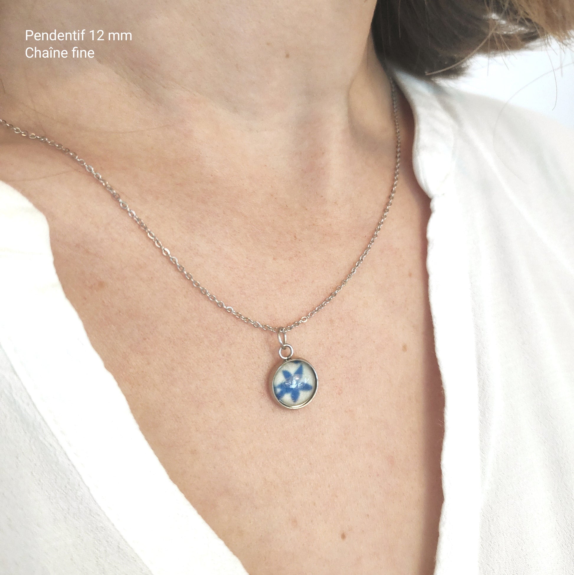 Collier artisanal porté, chaîne couleur argent 1.2 mm, pendentif 12 mm avec tissu incorporé sous la perle de verre.
