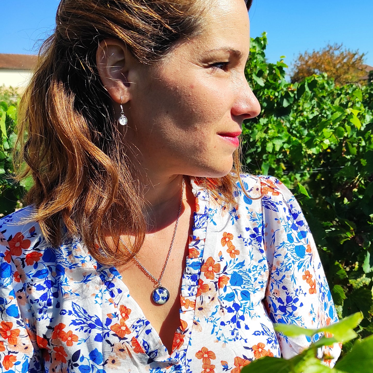 Collier acier inoxydable avec pendentif fleuri , motif fleurs bleues, avec fond blanc. Chaîne fine et pendentif de 18 mm, le collier est porté avec les boucles d'oreille assorties, création du tissu incorporé à l'intérieur du bijou et fabrication par Fanny Agustin.