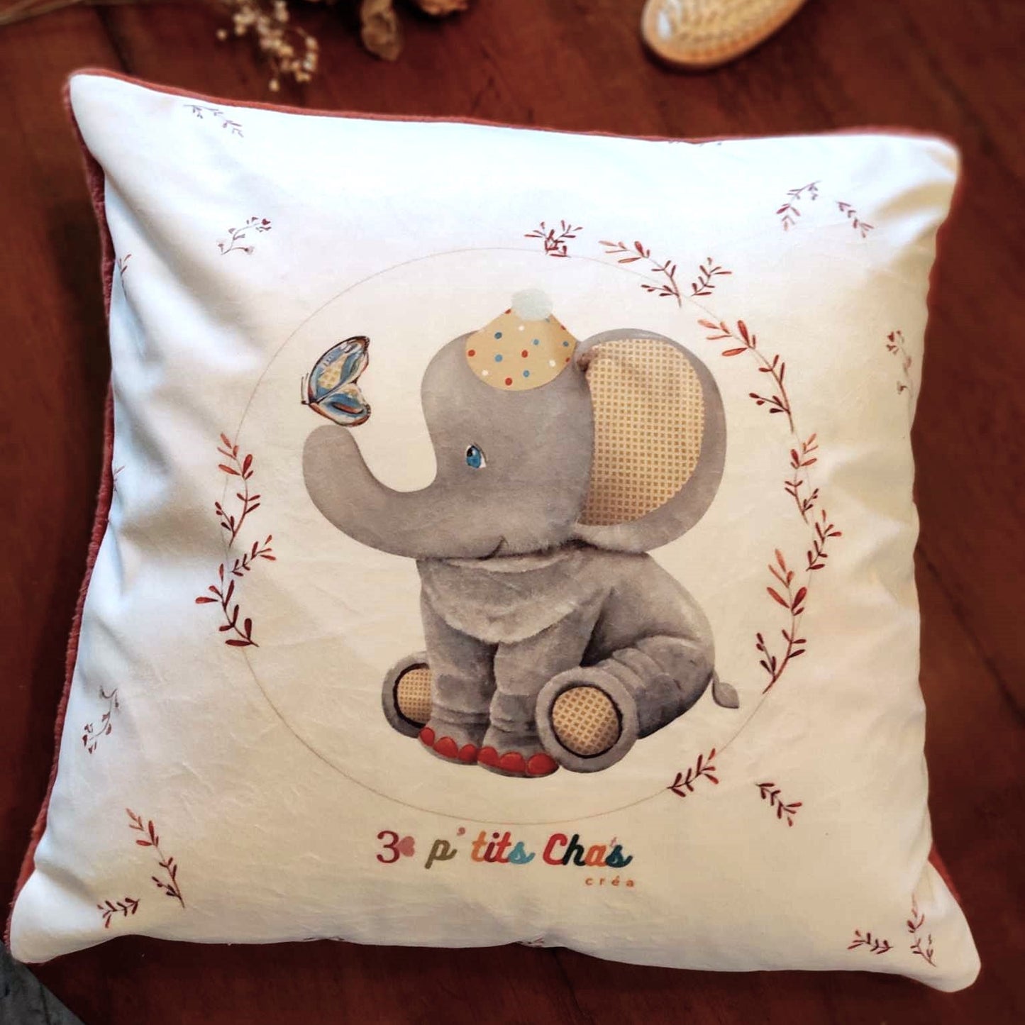Coussin en velours avec motif éléphant placé au centre sur fond blanc.