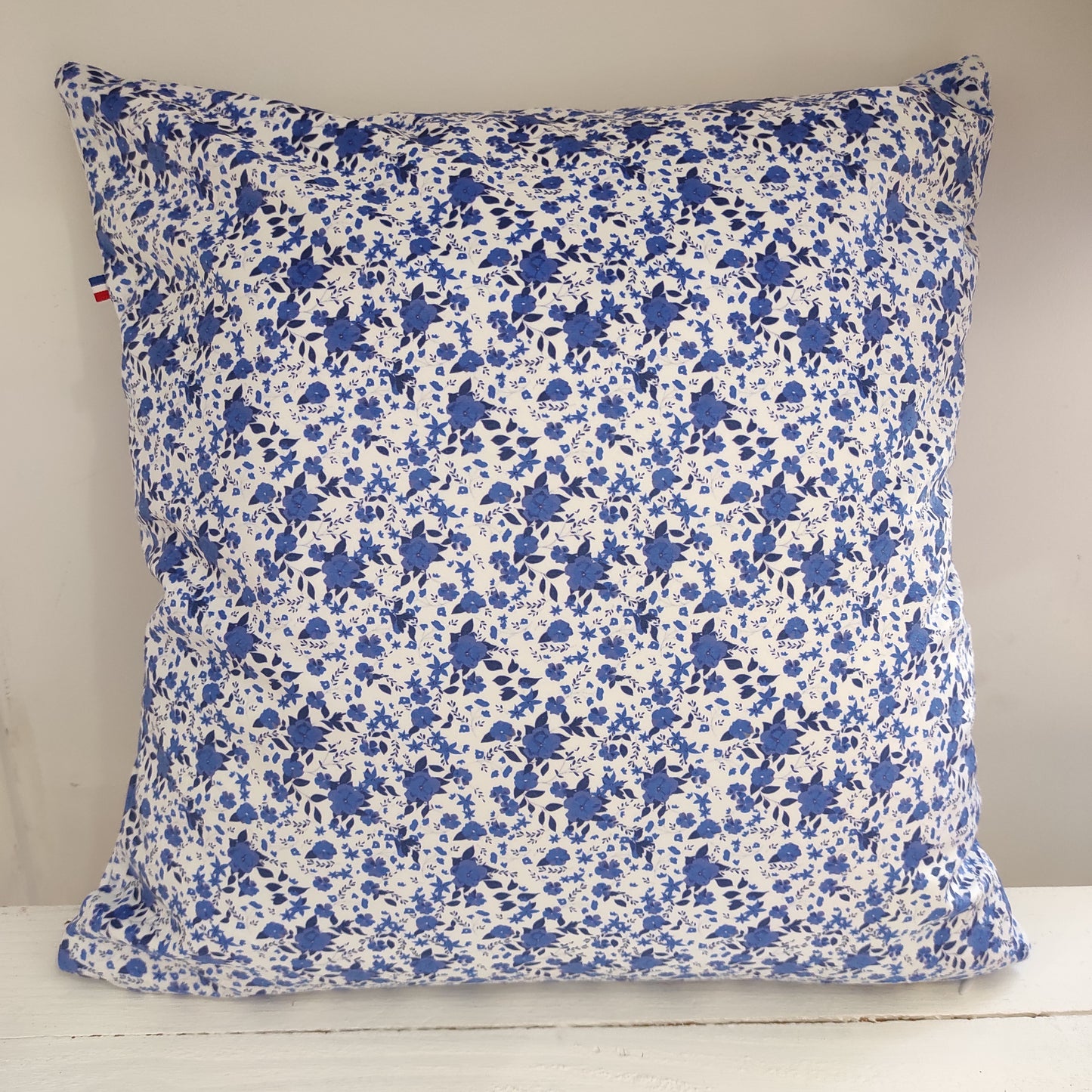 Coussin velours fleurs bleues, le fond est blanc avec des fleurs et feuillage bleus.