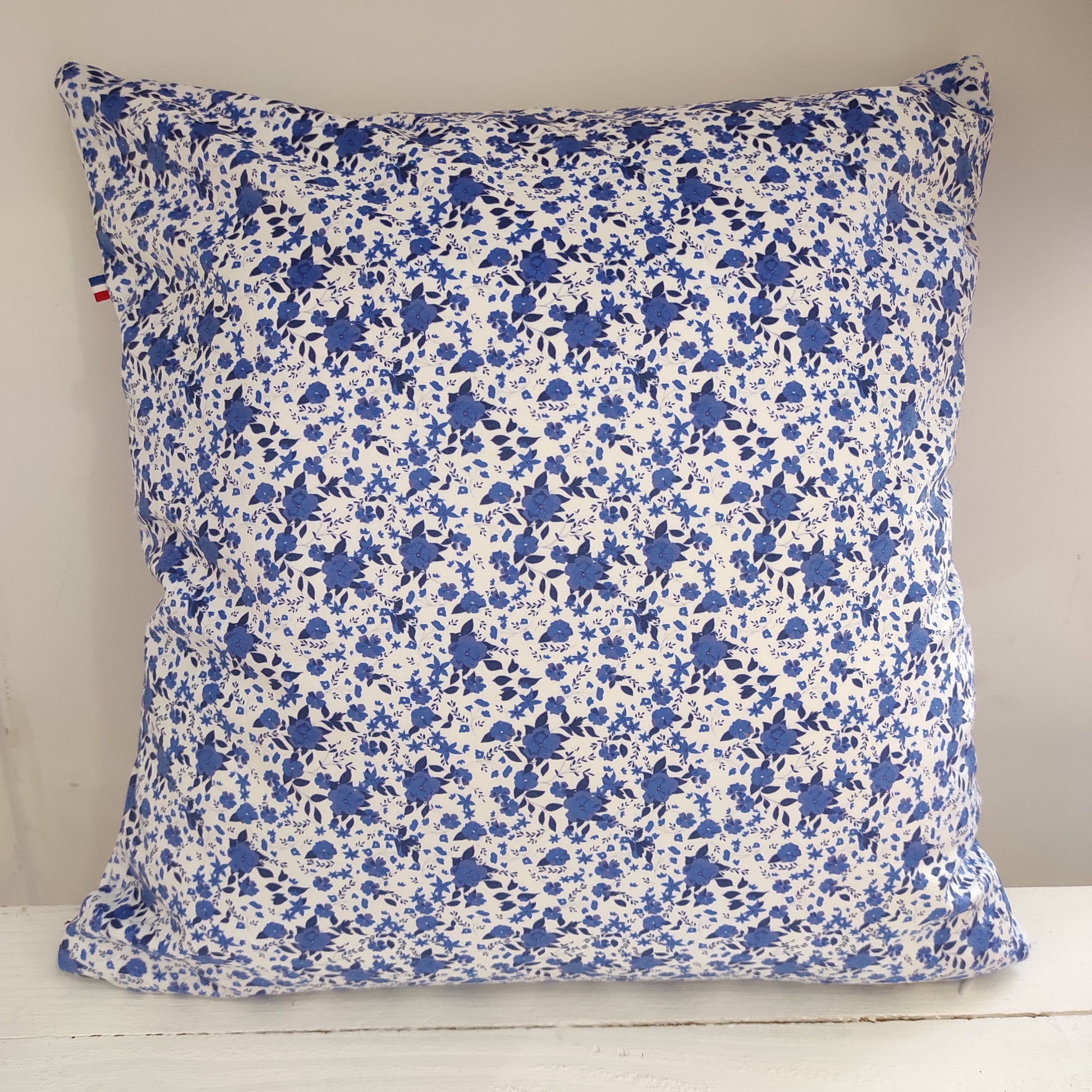 Coussin velours fleurs bleues, le fond est blanc avec des fleurs et feuillage bleus.