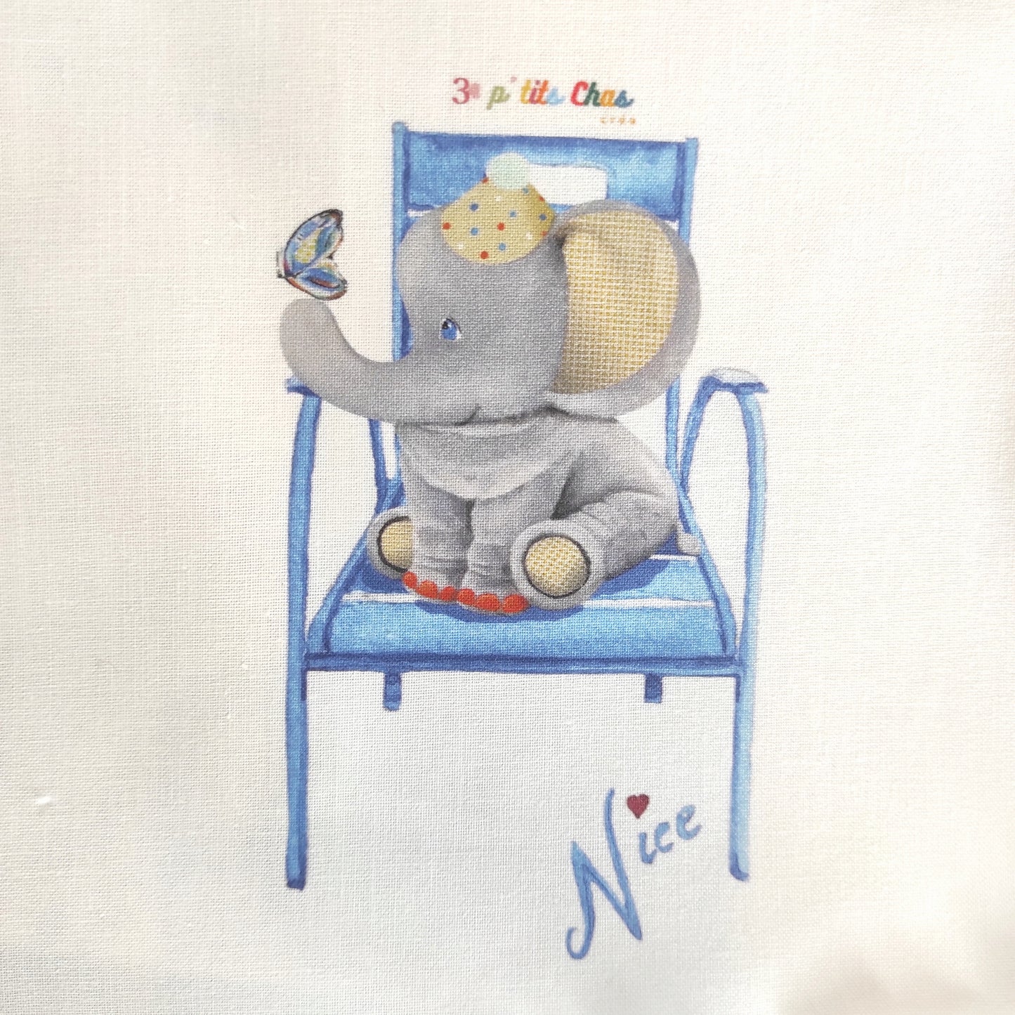 Eléphant dessiné à l'acrylique puis imprimé sur tissu en coton. Dessin exclusifs de FANNY AGUSTIN. L'éléphant est assis avec un papillon sur le nez. Il  un chapeau de clown sur la tête. Ses oreilles sont jaunes et le dessous de ces pattes également. Il est entouré de feuillage marron sur fond blanc.