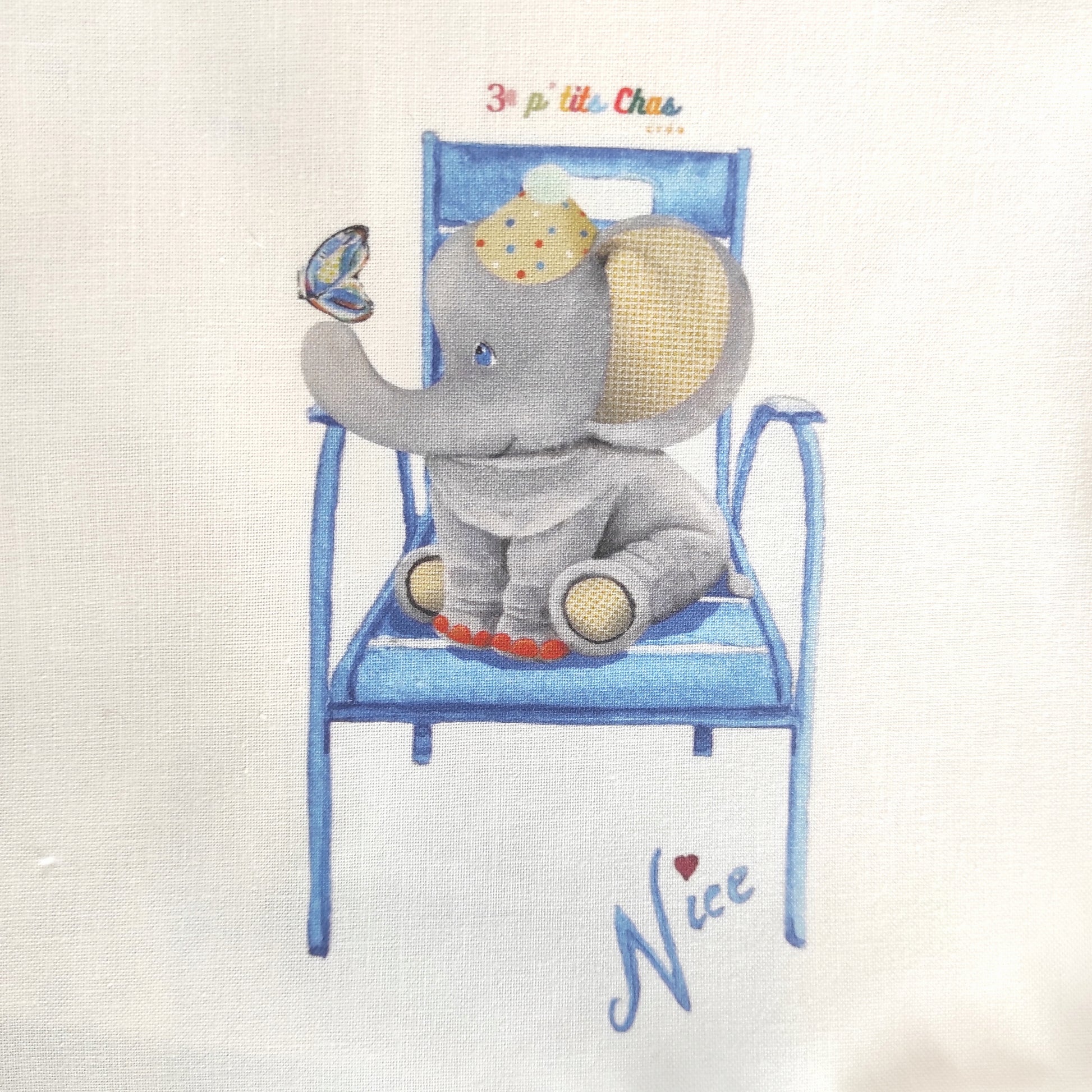 Eléphant dessiné à l'acrylique puis imprimé sur tissu en coton. Dessin exclusifs de FANNY AGUSTIN. L'éléphant est assis avec un papillon sur le nez. Il  un chapeau de clown sur la tête. Ses oreilles sont jaunes et le dessous de ces pattes également. Il est entouré de feuillage marron sur fond blanc.