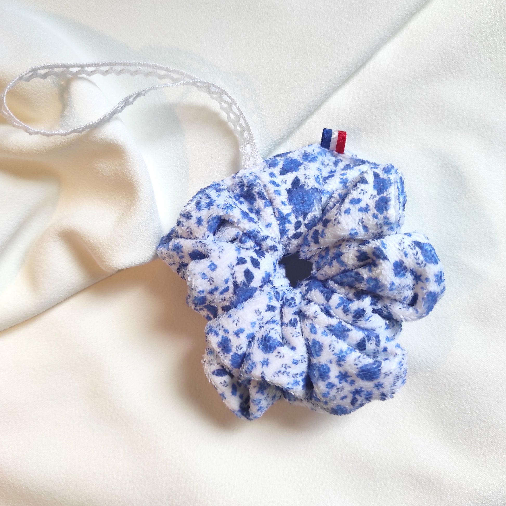 Fleurs de douche motif fleurs bleues dessiné par Fanny Agustin. Les fleurs bleues sur fond blanc. Un ruban en dentelle pour accrocher au poignet est présent avec ruban bleu blanc rouge, made in France.