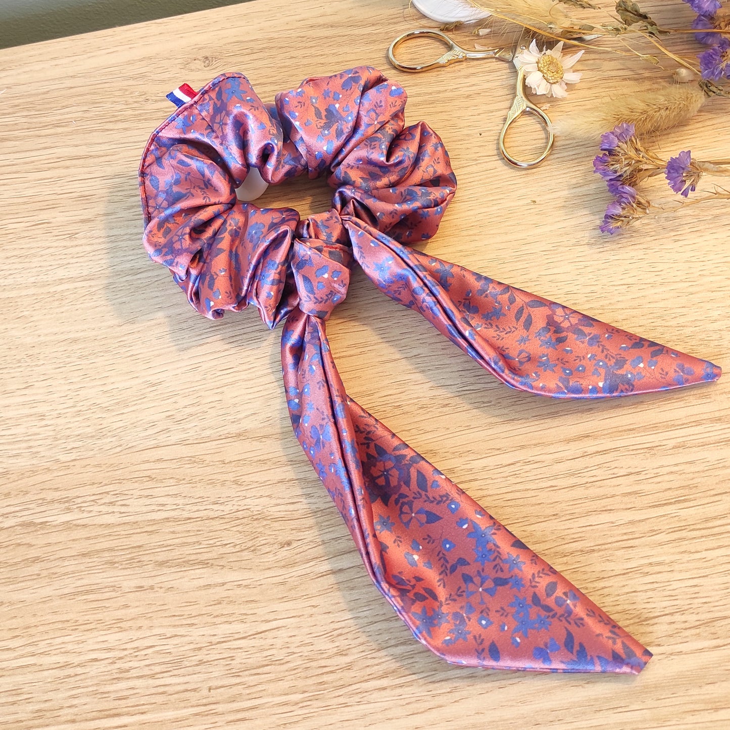 Chouchou foulchie motif fleuri avec fleurs bleues et fond couleur paprika. 