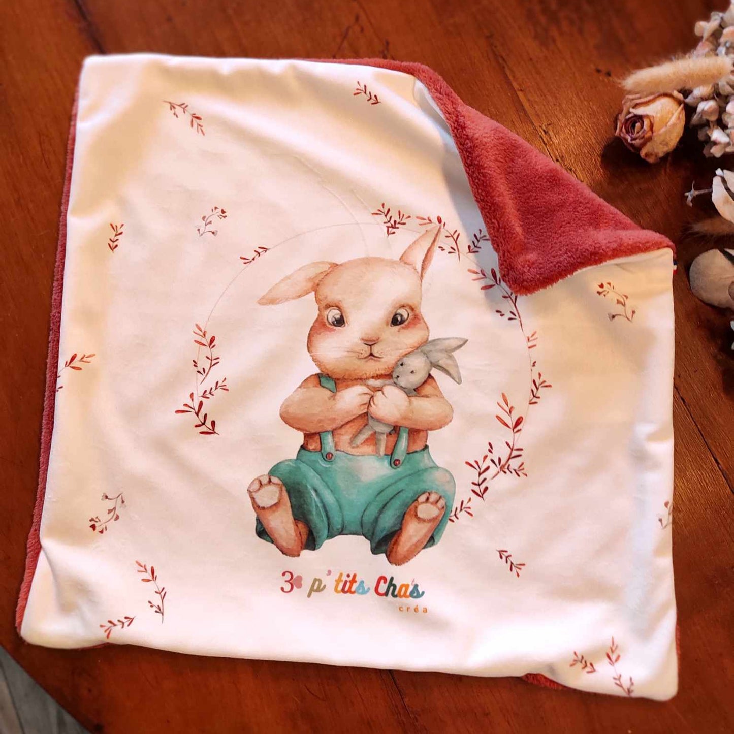 Housse de coussin avec le tissu du dessous qui apparaît en angle, l'envers est de couleur paprika en paille peluche.