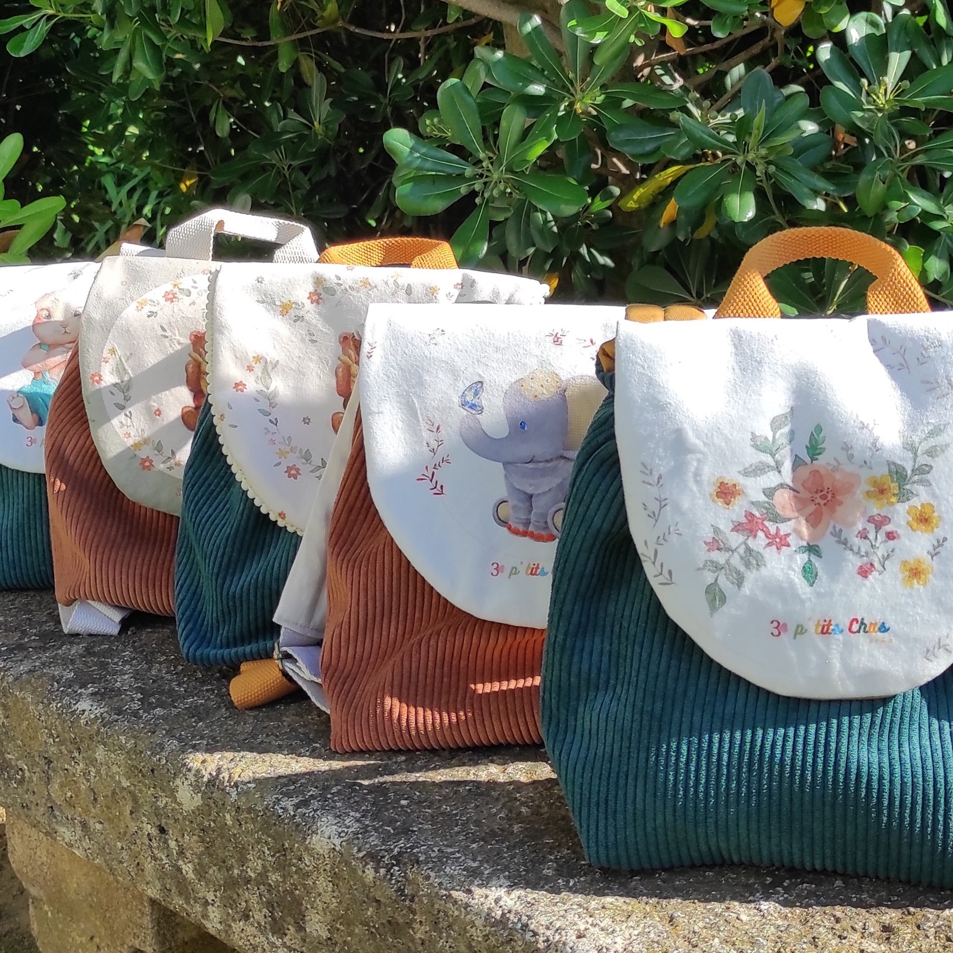 Plusieurs sacs à dos exposés sur un banc, avec différentes couleur et motifs différents. 