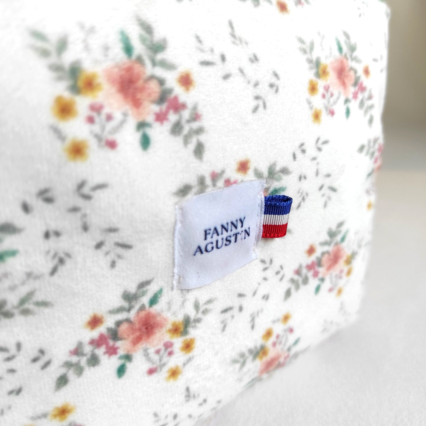 Détail du logo avec ruban bleu blanc rouge sur velours fleuri Fanny Agustin.