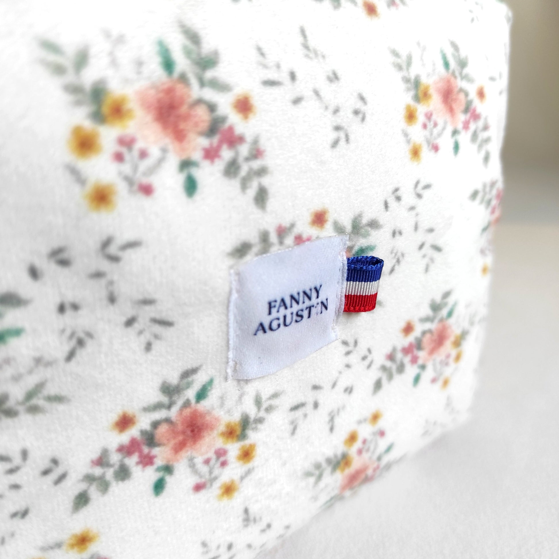 Détail du logo avec ruban bleu blanc rouge sur velours fleuri Fanny Agustin.