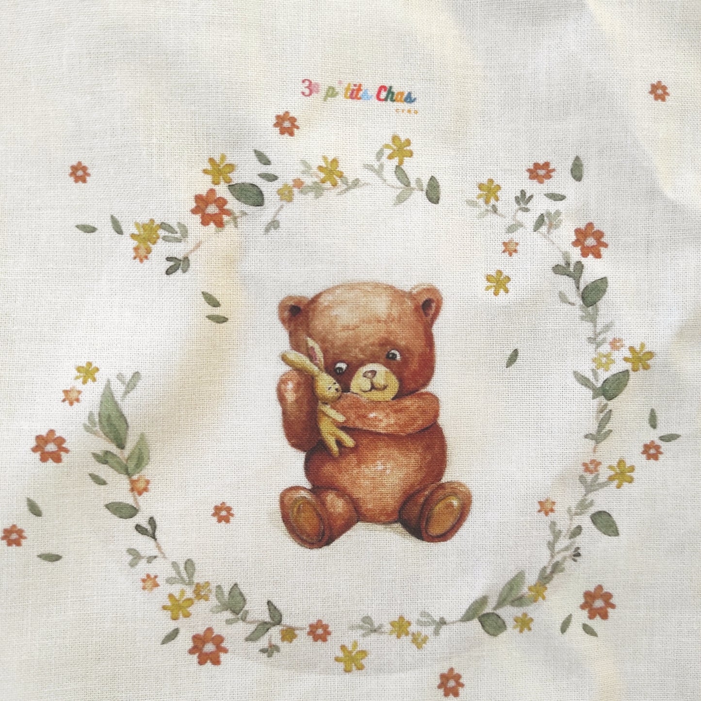 Ourson dessiné à l'aquarelle puis imprimé sur tissu en coton. Dessin exclusifs de FANNY AGUSTIN. L'ourson tient un doudou dans ses bras et est entouré de feuillage et fleurs marrons, jaunes et oranges.