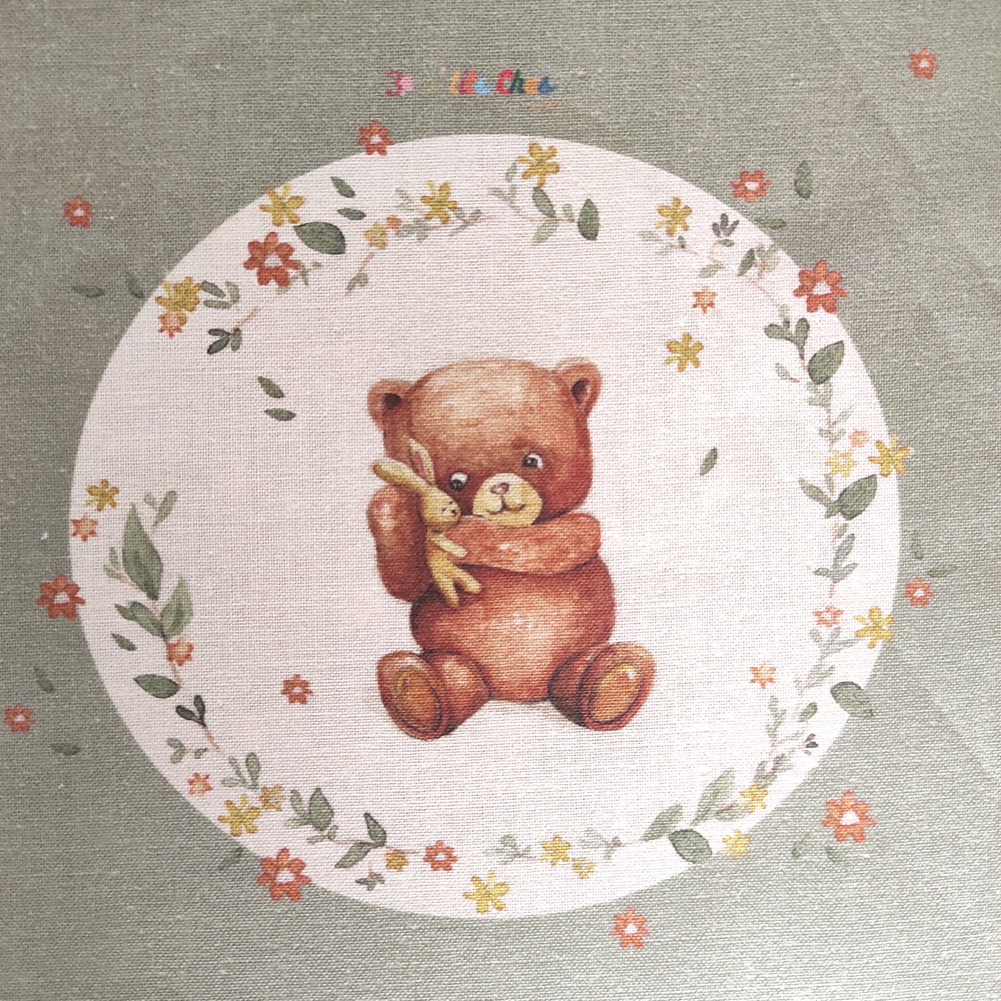 Ourson dessiné à l'aquarelle puis imprimé sur tissu en coton. Dessin exclusifs de FANNY AGUSTIN. L'ourson tient un doudou dans ses bras et est entouré de feuillage et fleurs marrons, jaunes et oranges.