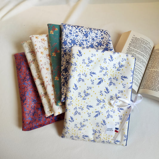 Pochettes à livre, format poche, en velours fleuri, imprimé localement, fabrication Française et artisanale. Les motifs sont dessinés par Fanny Agustin et la pochette est fabriquée par ses soins à la main. Sur la photographie,   pochettes sont présentées avec les différents motifs pour personnaliser la pochette. La pochette se referme avec un ruban en satin blanc.