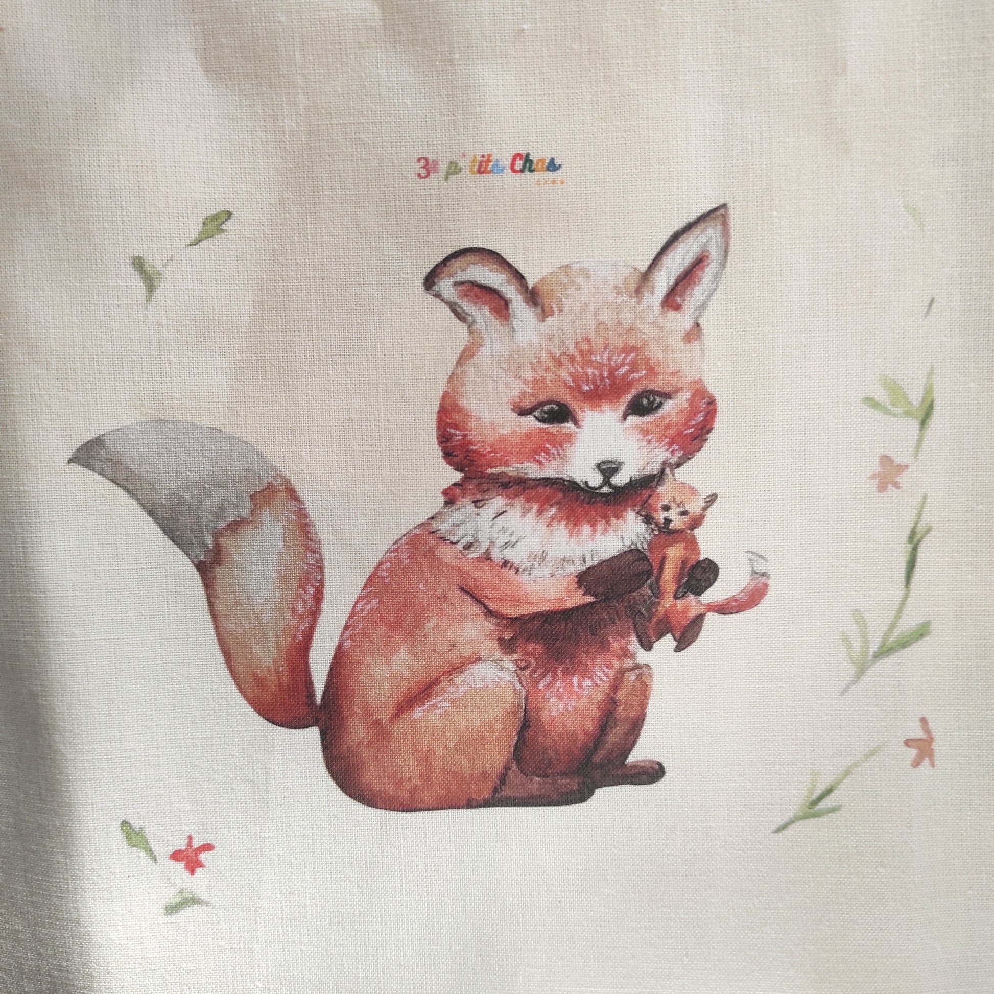 Renard dessiné à l'aquarelle puis imprimé sur tissu en coton. Dessin exclusifs de FANNY AGUSTIN. Le renard tient un doudou dans ses bras et est entouré de feuillage et fleurs oranges.