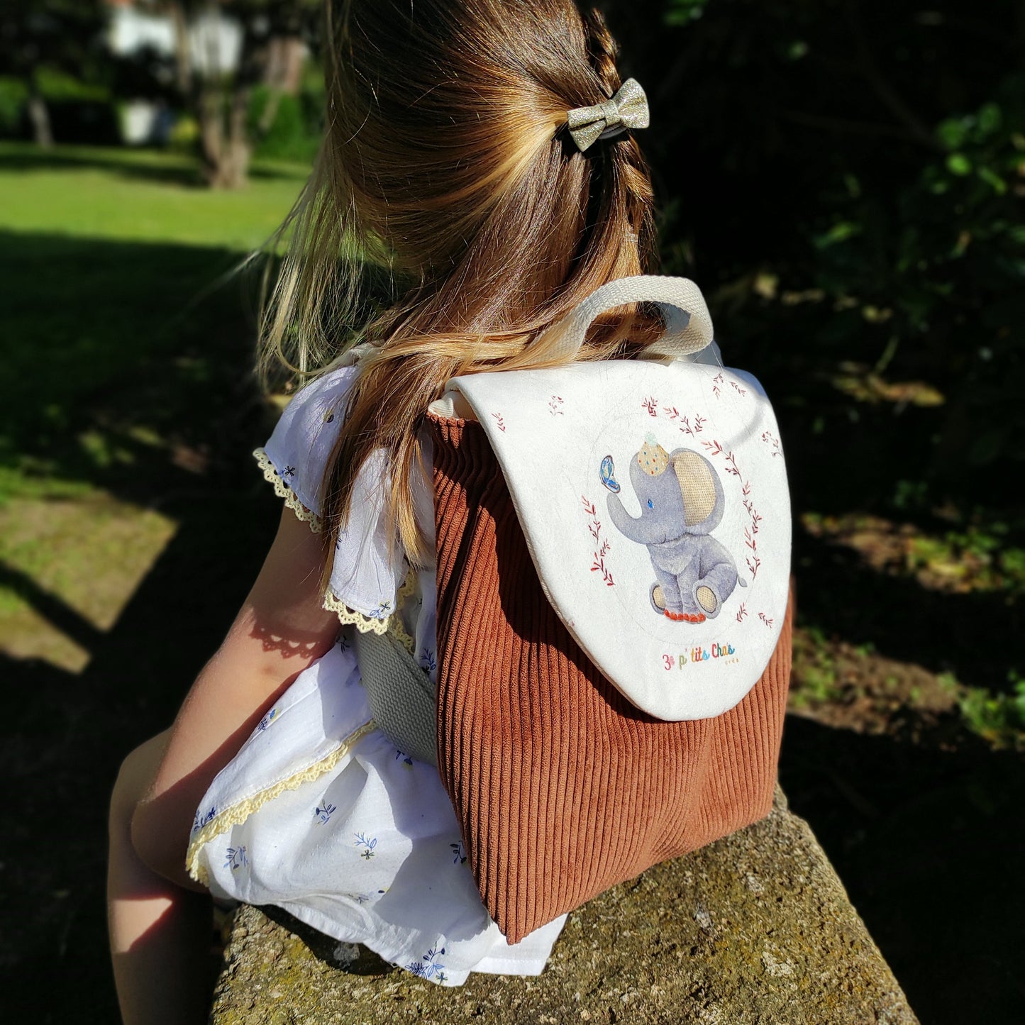 Sac à dos porté sur fillette, avec motif éléphant et velours côtelé marron.