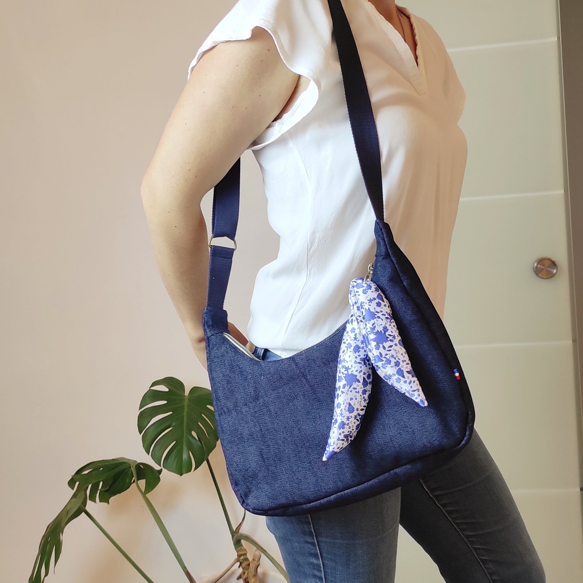 Sac en jean bleu foncé porté en bandoulière grâce à la sangle réglable. 