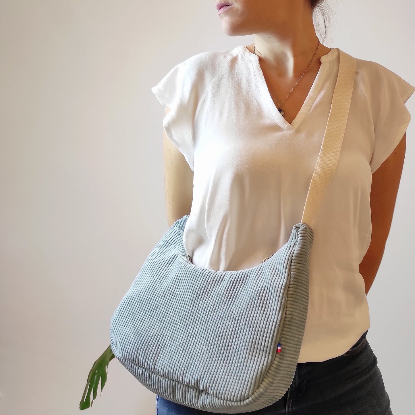 Sac à main fabriqué artisanalement à Cagnes-sur-Mer par Fanny Agustin. Sac besace velours côtelé vert de gris avec sangle écrue réglable. Le sac est porté en bandoulière.