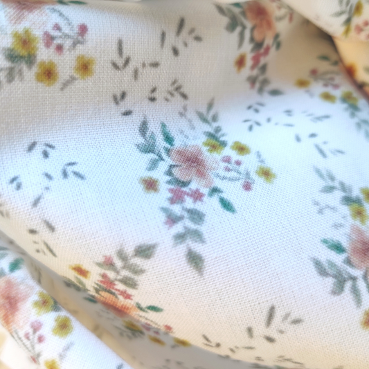 Tissu en cretonne de coton avec encre bio, motif fleuri, fleurs orange, jaune ose et feuillage vert sur fond blanc.