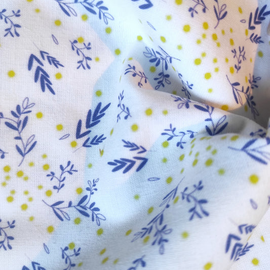 Tissu au motif exclusif mimosa création unique Fanny Agustin. Motif emblématique de la Côte d' Azur, le moif a des feuilles bleues et quelques points jaunes rappelant le mimosa, sur fond blanc.