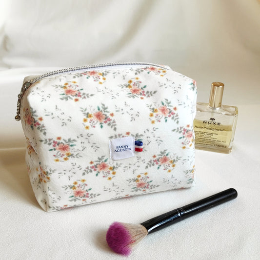 Trousse de toilette en velours doux imprimé localement et fabrication Française. Le dessin des fleurs est réalisé par Fanny Agustin ainsi que la fabrication à la main. 
La trousse en photographie est de taille normale, on peut y ajouter des accessoires à maquillage ou parfum comme représenté sur la photographie. Les motifs sont doux, avec du jaune, saumon et vert sur fond blanc.