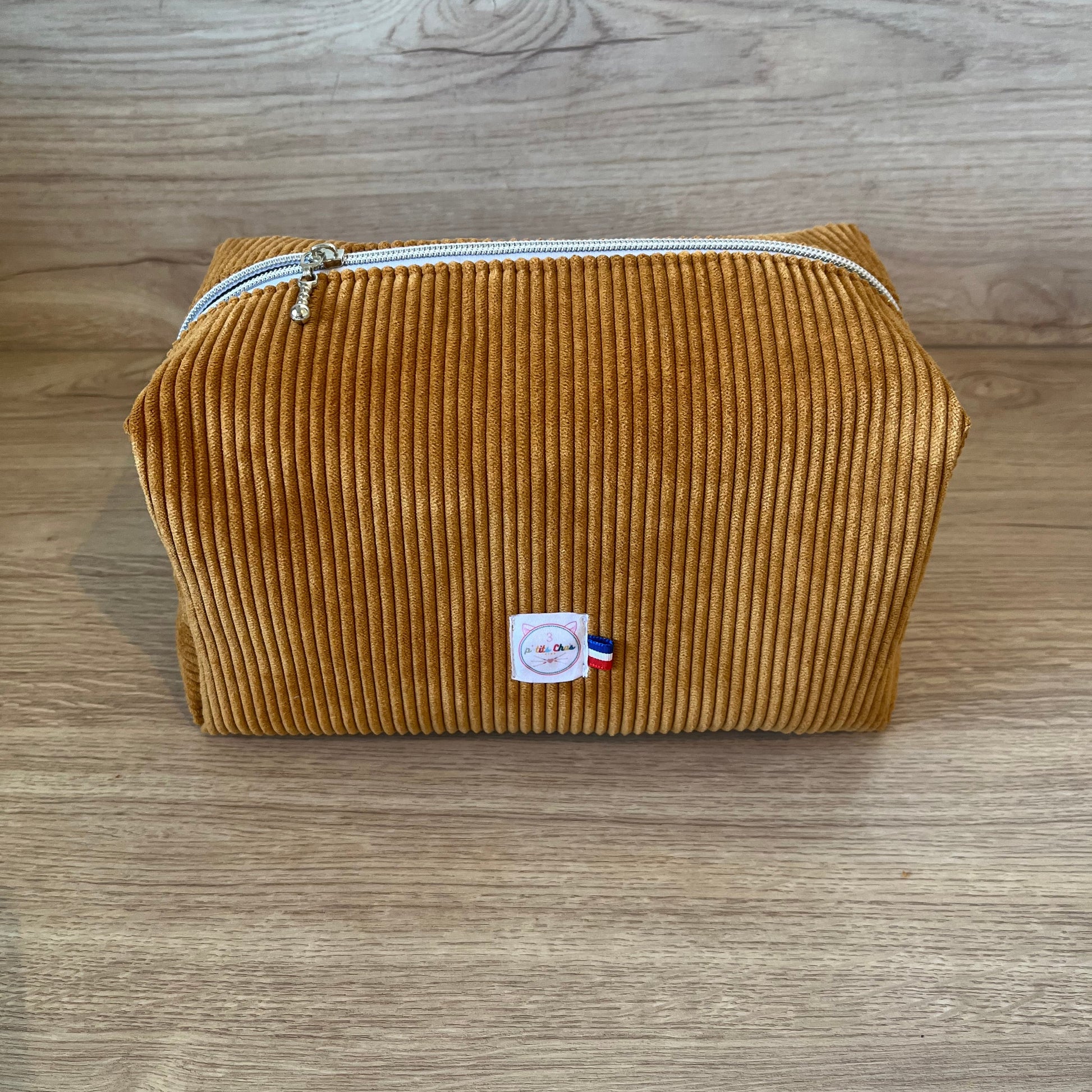 Grosse trousse de toilette en velours côtelé de couleur jaune moutarde, avec fermeture éclair argentée, logo et ruban bleu blanc rouge, fabrication Française artisanale.