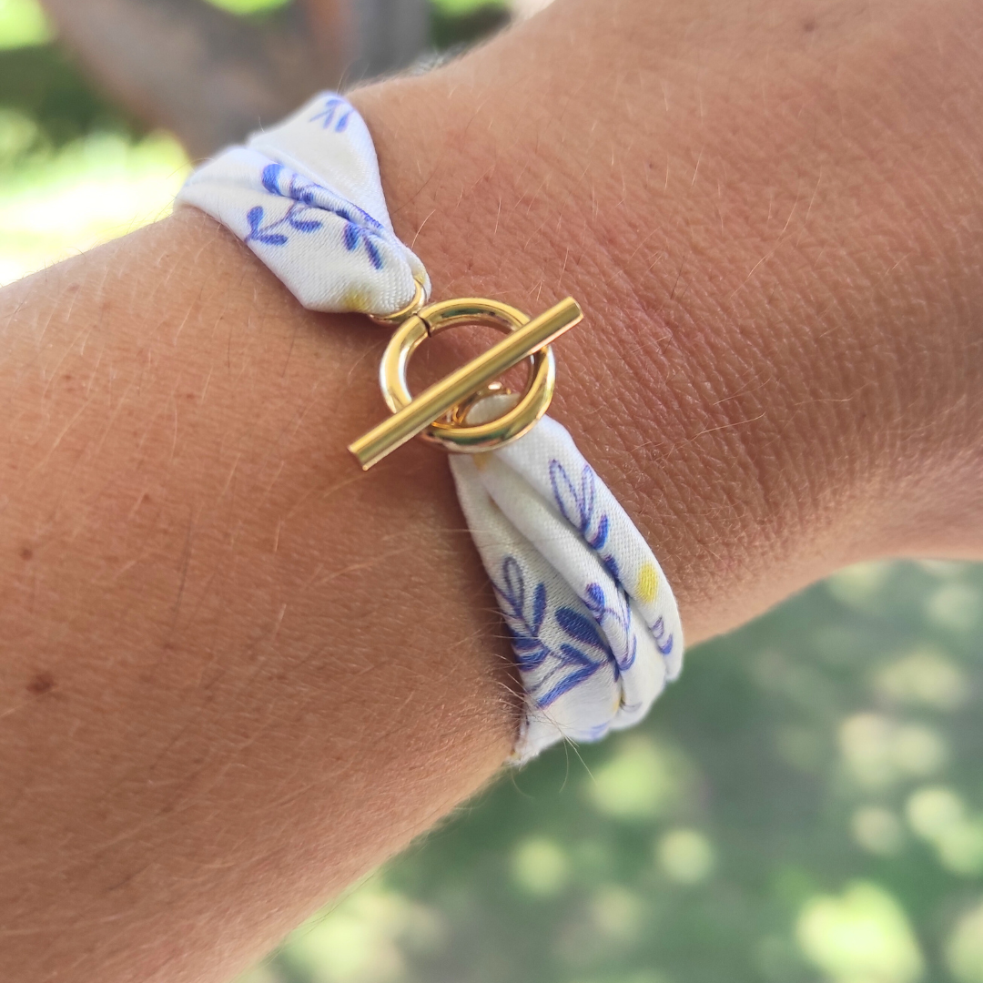 Bracelet en tissu satin motif mimosa, feuilles stylisées bleues et quelques touches de jaune, avec fermoir anneau en acier inoxydable.